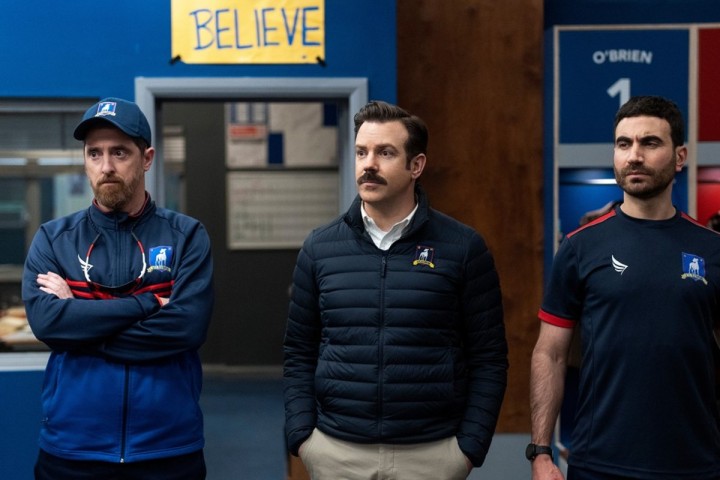 Ted and two men stand in a locker room in Ted Lasso season 3.
