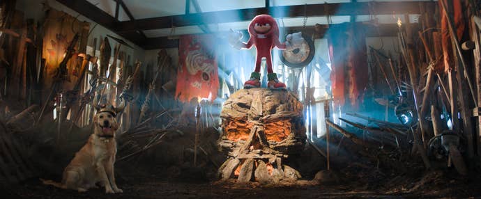 Knuckles, in live action, stands atop a stone icon in a slapdash gladitorial arena built into a living room.